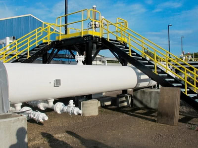 Pipeline infrastructure with access stairs at a utility site.