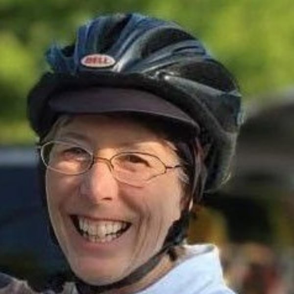 Bike helmet and smiling woman outdoors, enjoying a sunny day with a cheerful expression.
