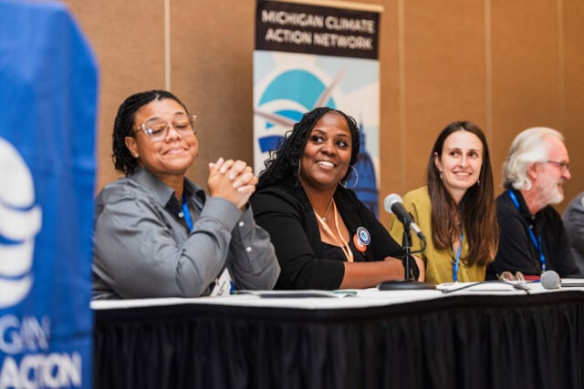 Diverse panel at climate action conference speaking into microphones.