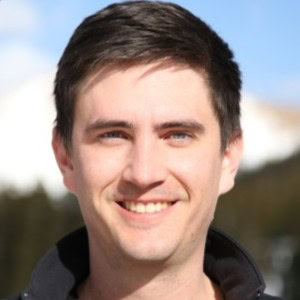Gabriel Vanloozen smiling outdoors with a clear blue sky background.