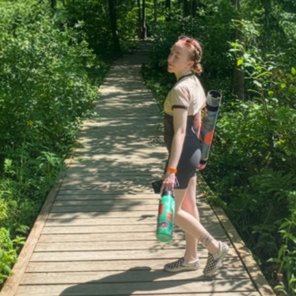 Reusable water bottle, Madi Burt walking on nature trail, eco-friendly lifestyle, Michigan Climate Action Network environmental efforts, sustainable living, conservation.