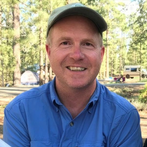 Mike Smalligan smiling outdoors in nature.