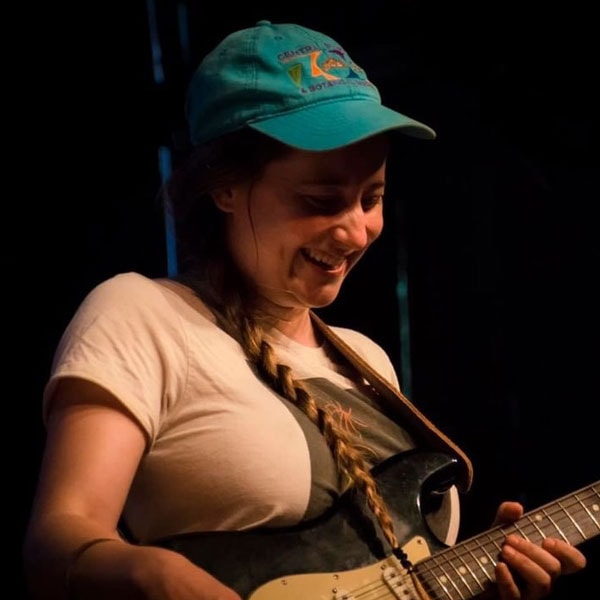 Samantha Cooper with guitar, smiling during climate advocacy event.