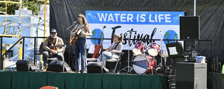 Michigan Climate Action Network logo on stage at Water Is Life Festival.